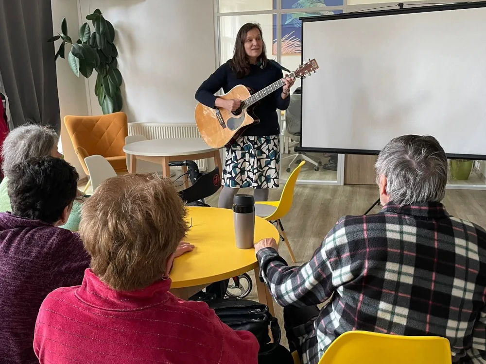 Muzikoterapeutka hraje na kytaru pro &uacute;častn&iacute;ky Kdyňsk&eacute; akademie vzdělan&eacute;ho seniora během setk&aacute;n&iacute; o hudbě.