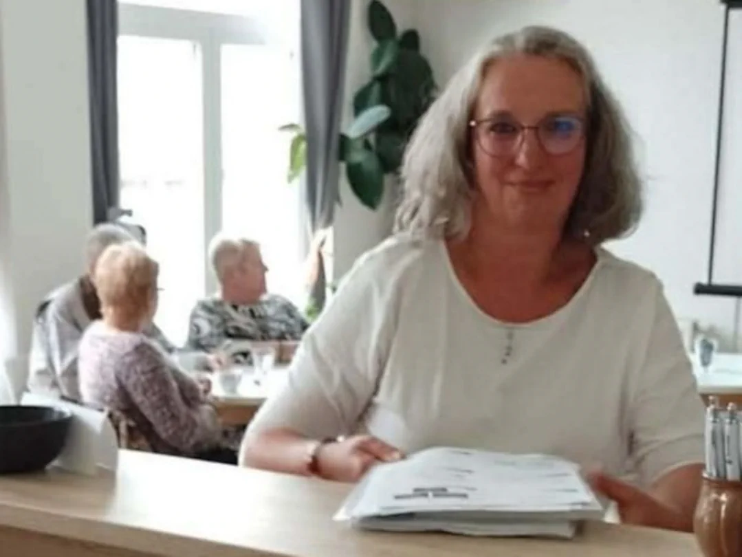 Lektorka tréninku paměti s pracovními podklady v Krámečku ve Kdyni, v pozadí sedí účastnice setkání.